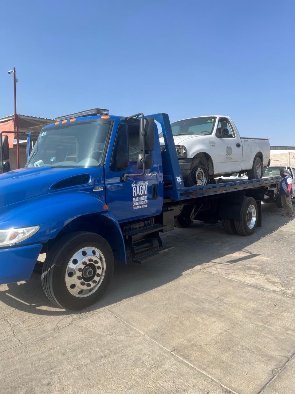 Grúa de plataforma trasladando camioneta